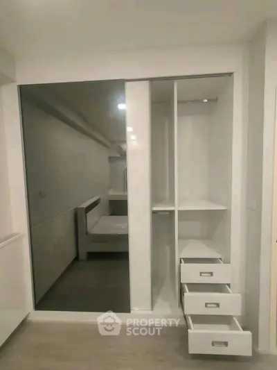 Spacious modern wardrobe with sliding mirror doors and open drawers in a stylish bedroom.