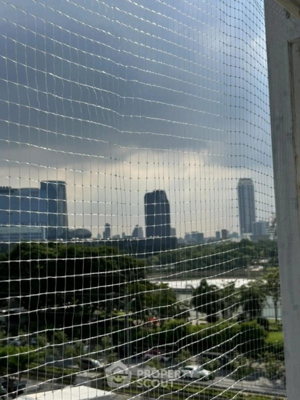 Stunning cityscape view from a high-rise balcony with safety netting.