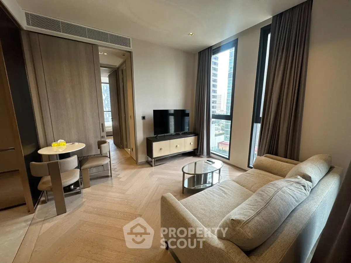 Modern living room with stylish furniture and large windows in a high-rise apartment.