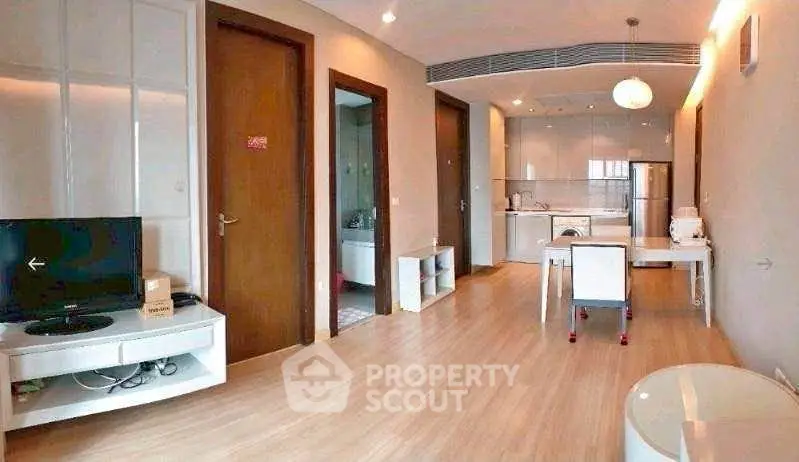 Modern open-plan living room with sleek kitchen and wooden flooring in a stylish apartment.