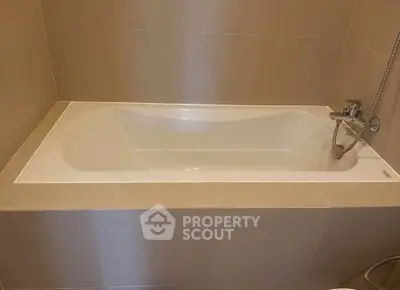 Modern bathroom with sleek built-in bathtub and neutral tile design.