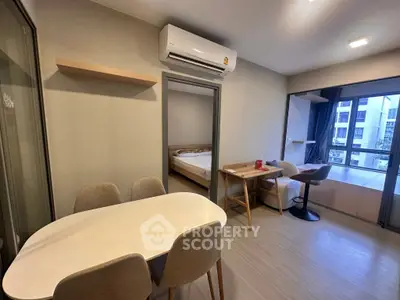 Modern apartment interior with dining area, study desk, and bedroom view, featuring sleek design and natural light.