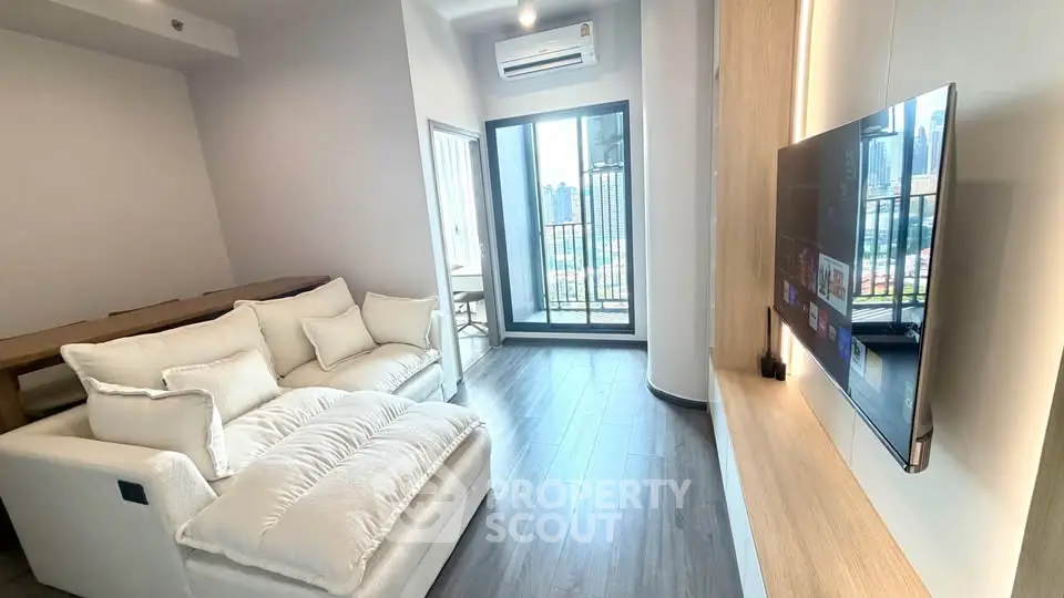 Modern living room with plush sofa and balcony view in high-rise apartment.