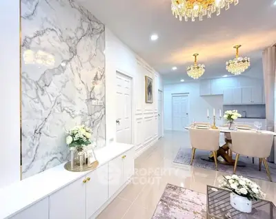 Luxurious open-plan living and dining area with elegant chandeliers and marble accents.