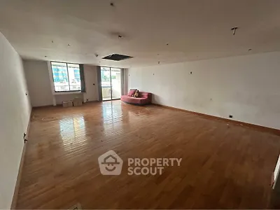 Spacious unfurnished room with wooden flooring and large window, ideal for customization.
