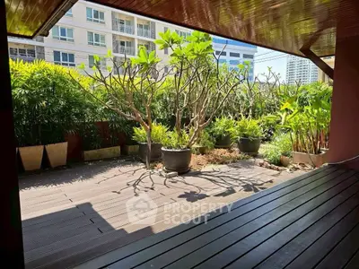 Spacious balcony with lush greenery and modern wooden decking in urban setting.