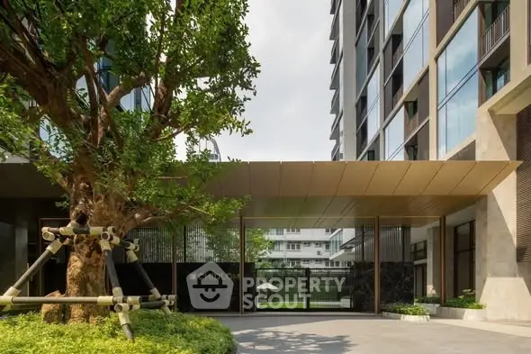 Modern building entrance with lush greenery and sleek architectural design.
