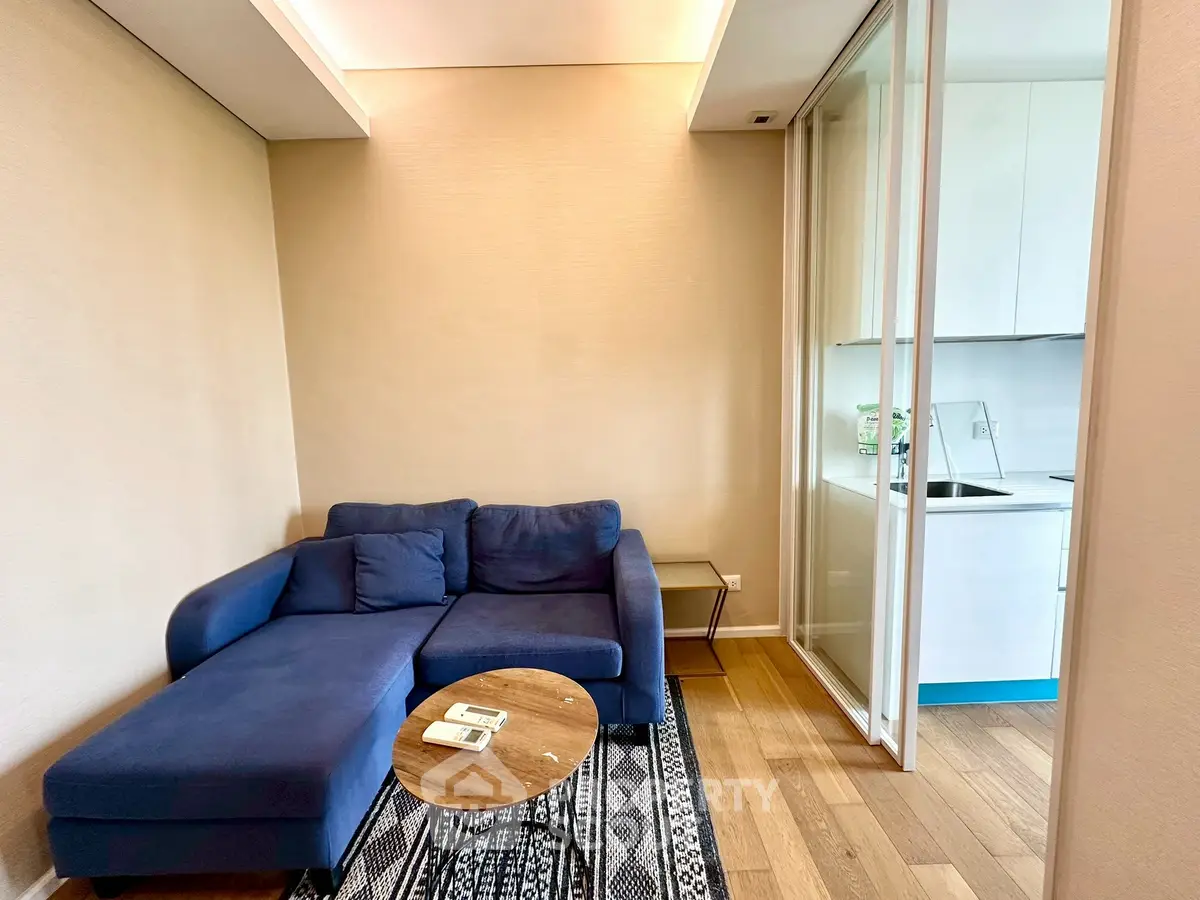 Cozy living room with blue sofa and modern kitchen in open layout apartment.