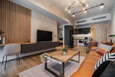 Modern living room with stylish decor and open kitchen layout, featuring a cozy seating area and contemporary lighting.