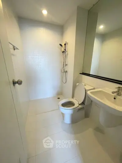 Modern bathroom with sleek fixtures and white tiles, featuring a shower and toilet.