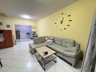 Spacious living room with modern sectional sofa and wall clock, perfect for family gatherings.