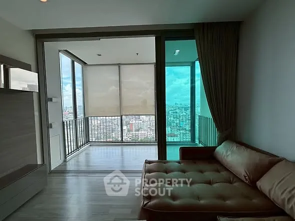 Spacious living room with large windows offering stunning city views and a cozy seating area.
