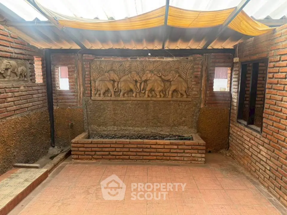Charming rustic courtyard with brick walls and elephant carvings, perfect for serene outdoor living.