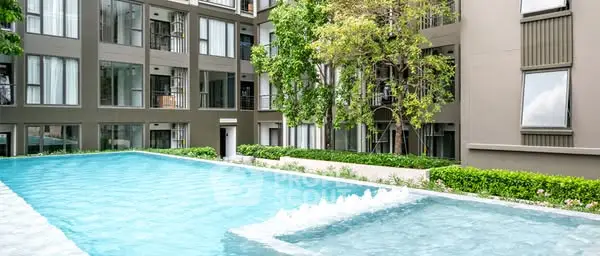 Modern apartment complex with refreshing outdoor pool and lush greenery.