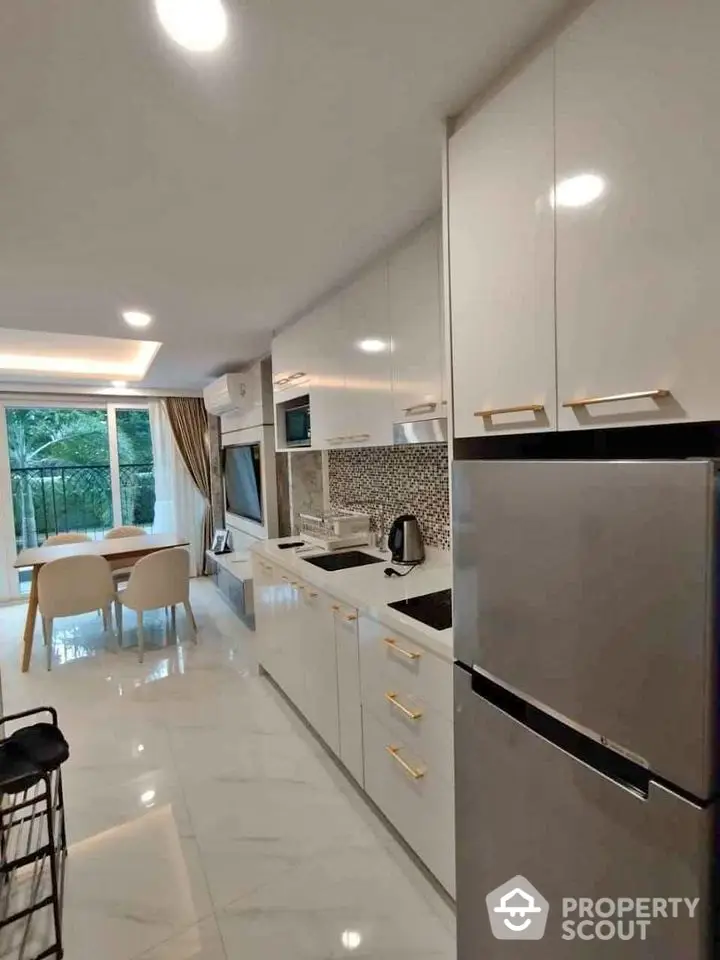 Modern kitchen with sleek white cabinets and dining area overlooking lush greenery.