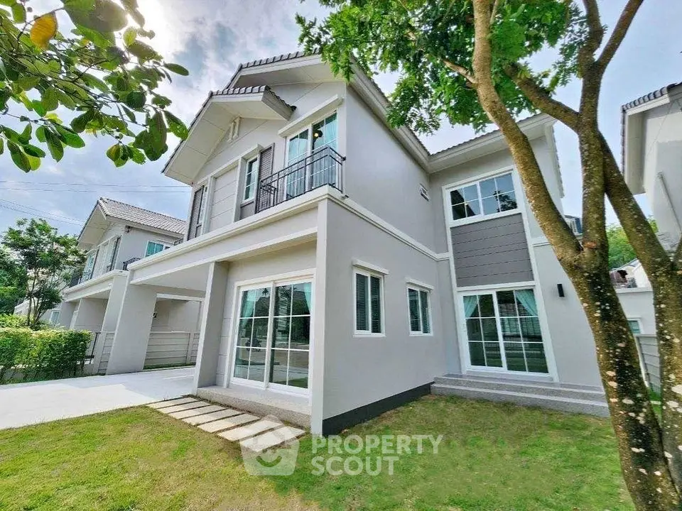 Modern two-story house with lush garden and large windows for natural light.