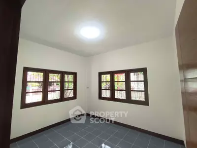 Bright empty room with tiled floor and large windows, perfect for customization.