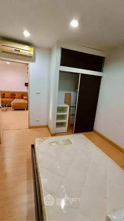 Cozy bedroom with open closet and view into living room, featuring modern furnishings and air conditioning.