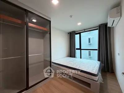 Modern bedroom with large window, built-in wardrobe, and air conditioning in a stylish apartment.