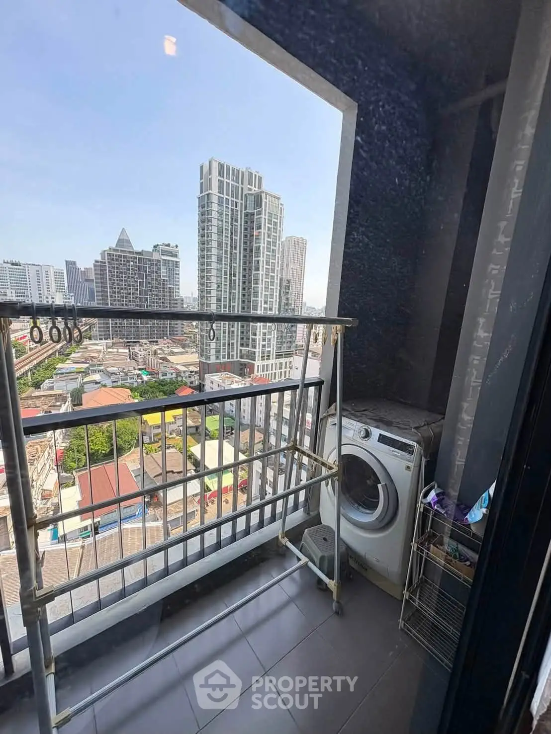 High-rise balcony with city view and washing machine, perfect for urban living.