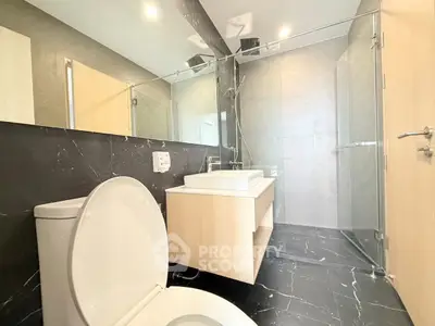 Modern bathroom with sleek design, featuring a glass shower and elegant fixtures.
