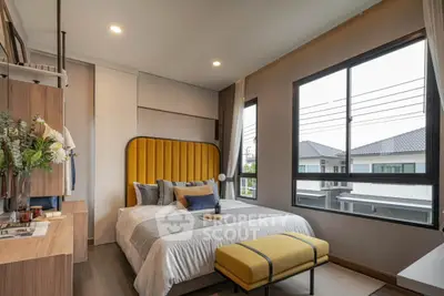 Modern bedroom with stylish decor and large windows offering natural light and neighborhood view.
