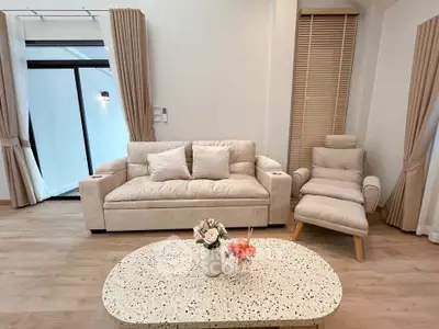 Elegant living room with cozy beige sofa and armchair, stylish coffee table, and floor-to-ceiling curtains.