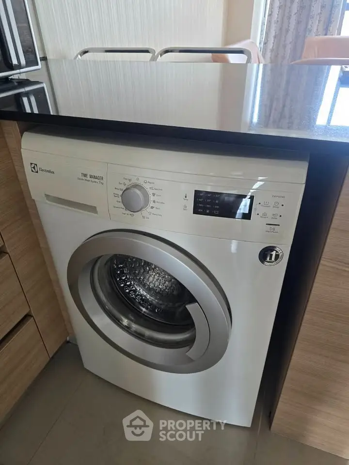 Modern kitchen with built-in Electrolux washing machine under sleek countertop.