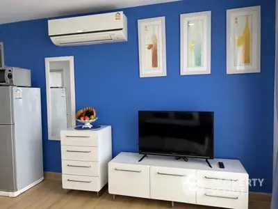 Modern living room with blue accent wall, sleek white furniture, and wall-mounted air conditioner.