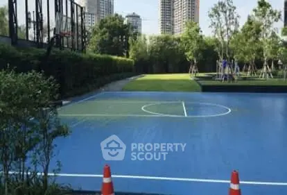 Modern residential complex with outdoor sports court and lush greenery.