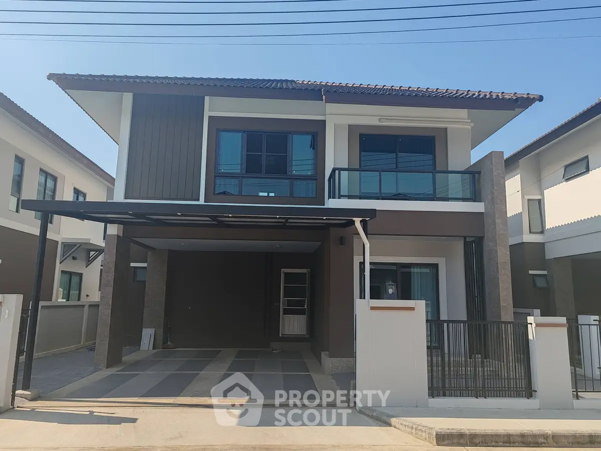Modern two-story house with spacious driveway and sleek balcony design.