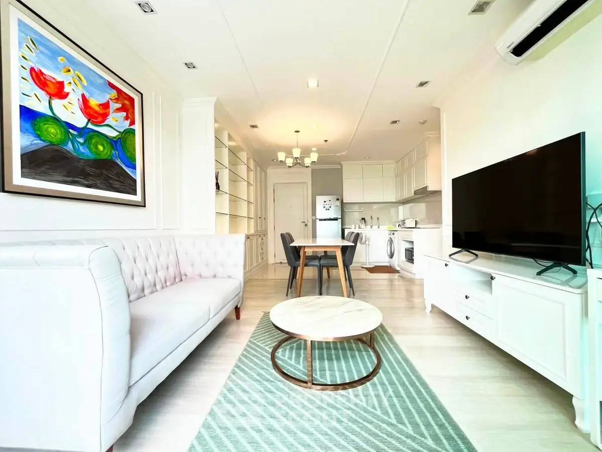 Bright and modern living room with open kitchen, stylish furniture, and vibrant artwork.