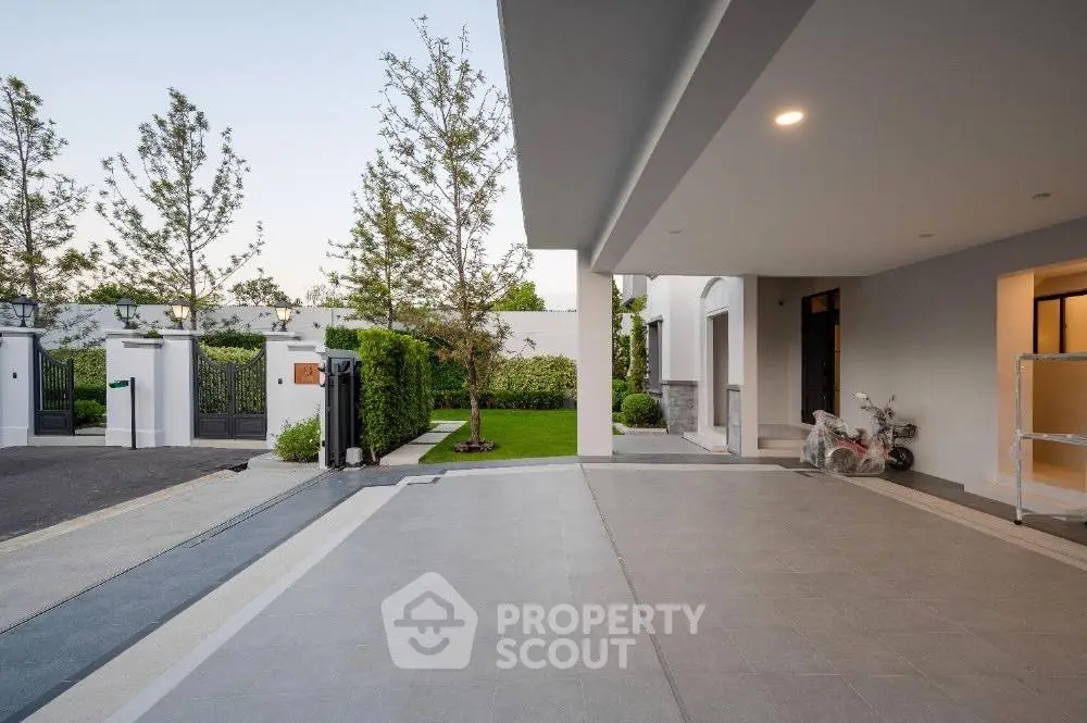 Modern residential entrance with spacious driveway and lush greenery