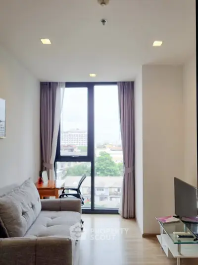 Modern living room with large window and city view, featuring a cozy sofa and work desk.