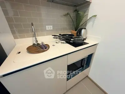 Modern kitchen with sleek countertop, built-in microwave, and stylish backsplash in a compact layout.