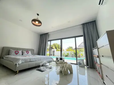 Luxurious bedroom with pool view, modern decor, and ample natural light in a serene setting.