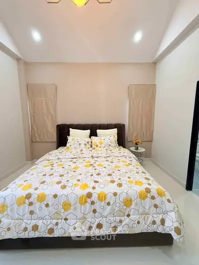 Cozy bedroom with modern decor and geometric patterned bedding in a bright, inviting space.