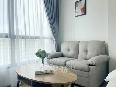 Chic living room with cozy sofa, elegant coffee table, and large window with city view.