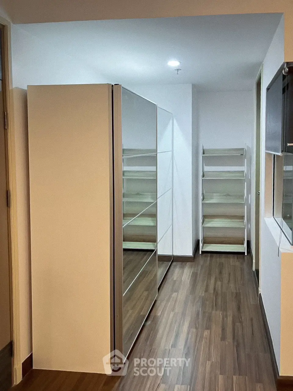 Spacious walk-in closet with modern shelving and wooden flooring in a contemporary home.