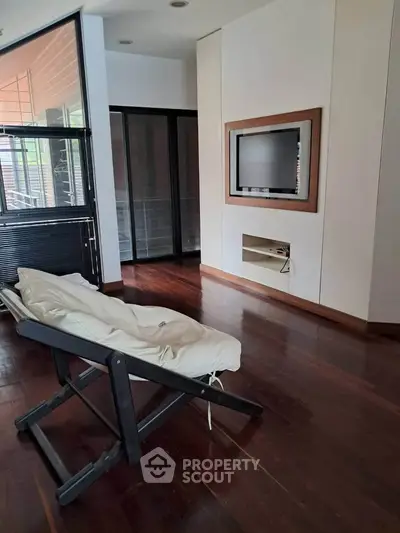 Modern living room with sleek wooden floors and built-in TV feature wall.