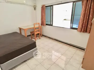 Cozy bedroom with tiled floor, window view, and simple furnishings in a compact space.