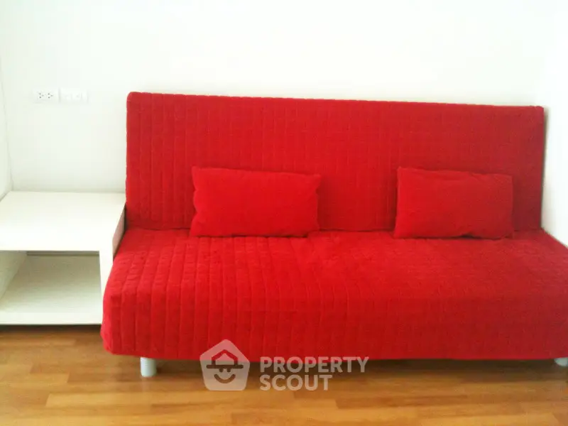 Modern living room with vibrant red sofa and sleek wooden flooring