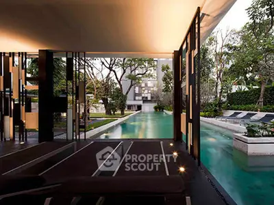Luxurious modern pool area with sleek design and lush greenery in upscale residential complex.