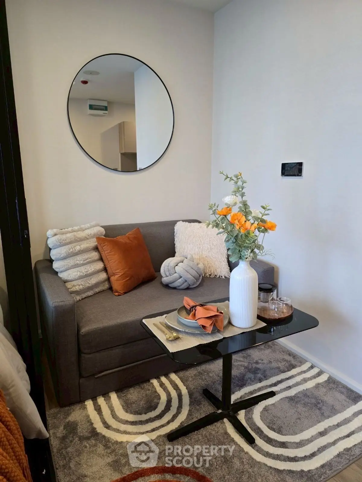 Cozy living room with stylish decor, featuring a plush sofa, decorative pillows, and a modern round mirror.