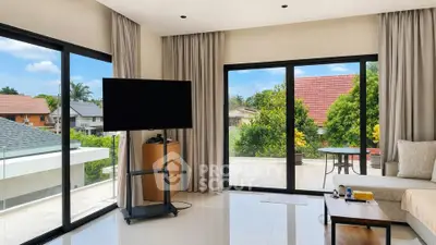 Spacious living room with large windows and balcony access, offering a bright and airy atmosphere.