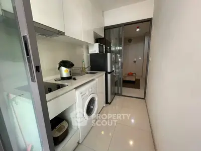 Modern kitchen with sleek appliances and washing machine in compact layout