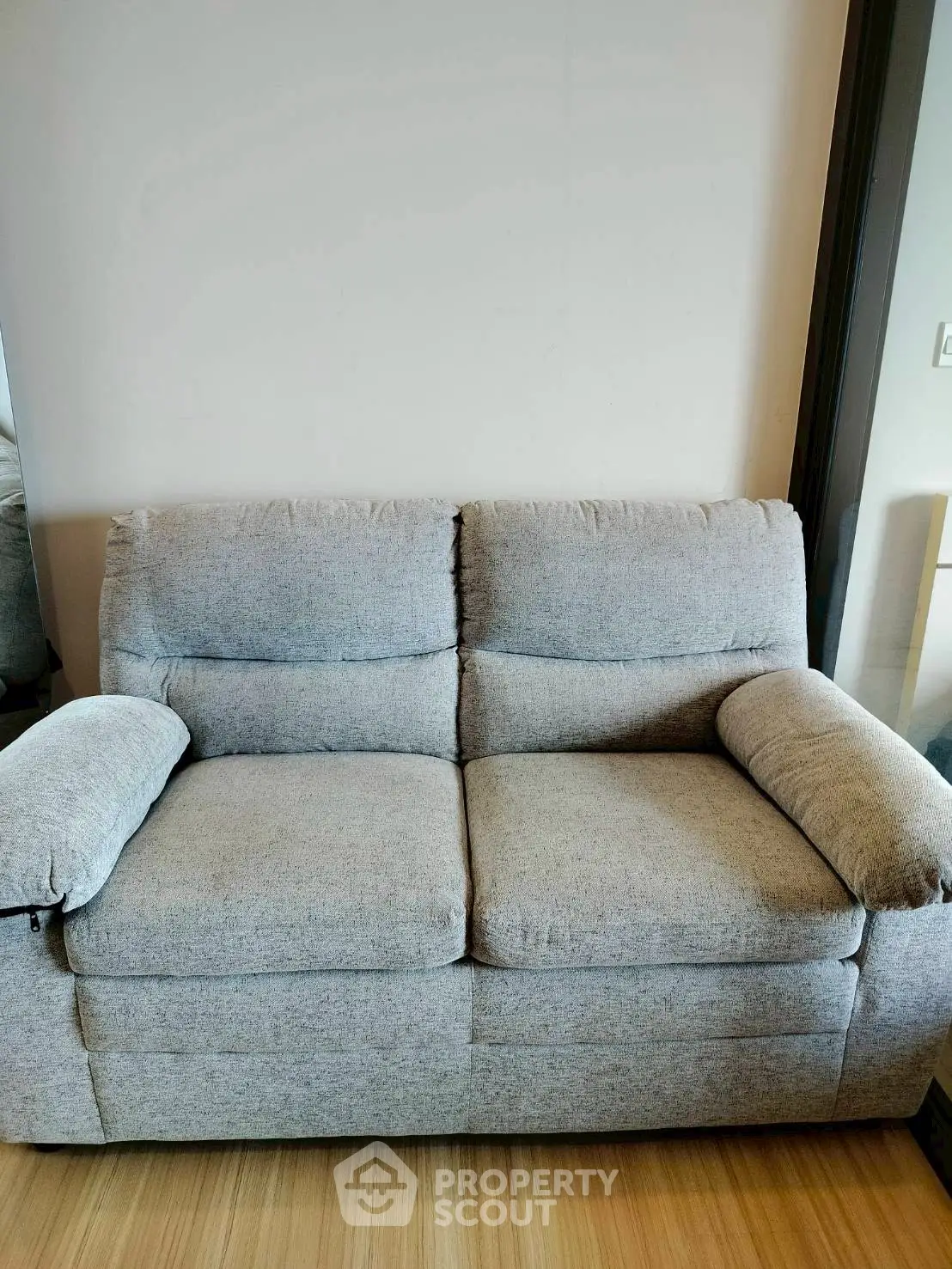 Cozy gray sofa in modern living room with wooden flooring, perfect for relaxation and comfort.