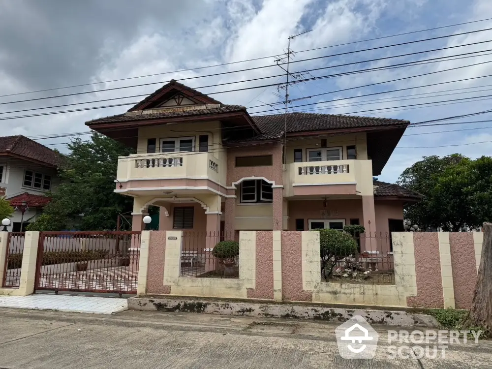 Charming two-story house with balcony and gated entrance in a serene neighborhood.