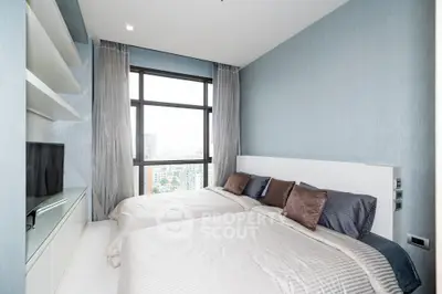 Modern bedroom with large window offering city view, featuring twin beds and sleek built-in storage.