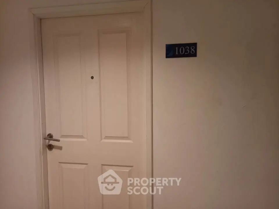 Apartment door with room number 1038 in a modern building hallway.